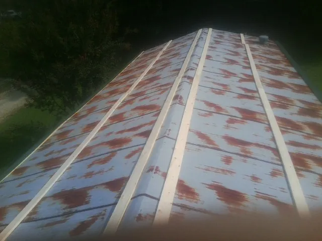 Rusted metal roof panels with new wood purlins before replacement in West Lafayette