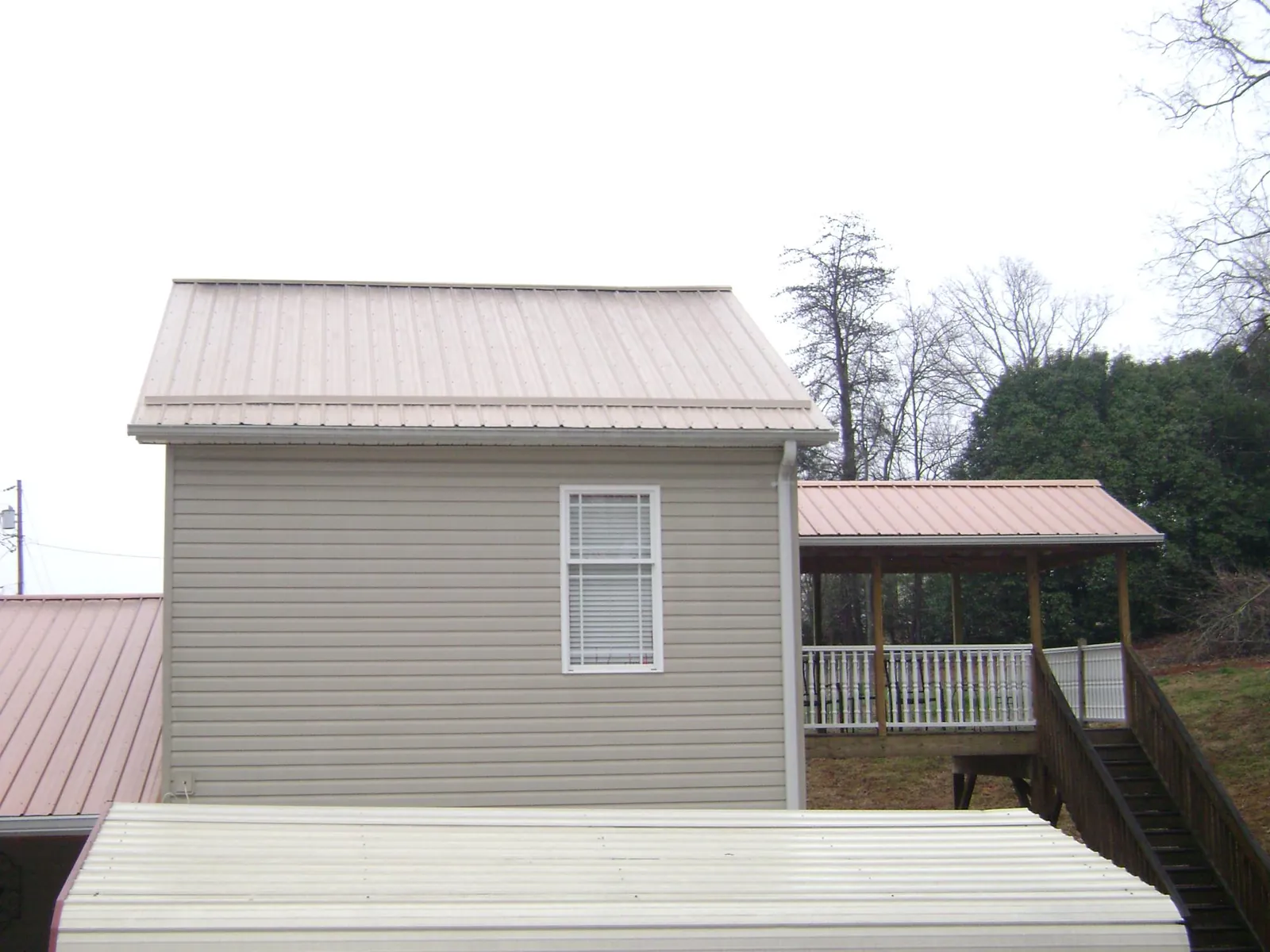 Tan metal roofs on a two story addition and attached porch, from a Roof Replacement job in West Lafayette